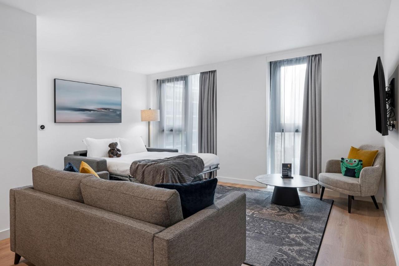 Citysuites 2 Aparthotel Manchester Exterior foto The photo shows a modern living space that incorporates a cozy and inviting atmosphere. It features a light-colored couch with colorful cushions, positioned in front of a coffee table. There's a comfortable armchair nearby, and a throw blanket is dra