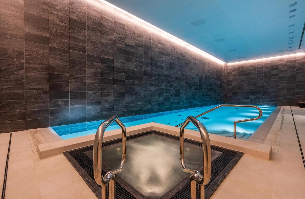 Citysuites 2 Aparthotel Manchester Exterior foto The photo shows a modern indoor swimming pool area. The pool features a sleek, rectangular design with a beautiful blue water that seems illuminated. Surrounding the pool are dark, textured walls, adding to the elegant atmosphere. There are dual meta