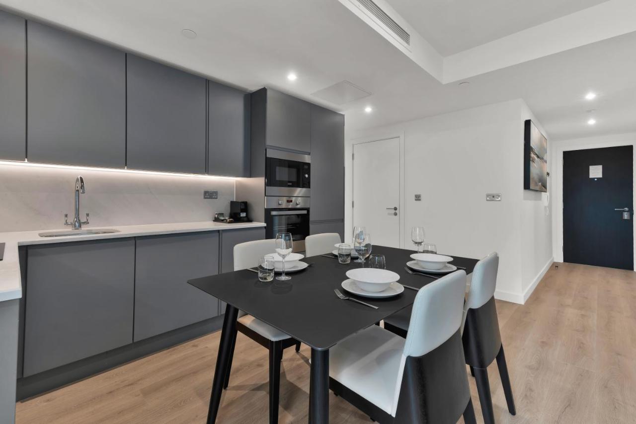 Citysuites 2 Aparthotel Manchester Exterior foto The photo shows a modern kitchen and dining area. There are sleek gray cabinetry and countertops, with a built-in oven and microwave. The kitchen is well-lit, featuring under-cabinet lighting that adds to the contemporary feel. In the dining area, th
