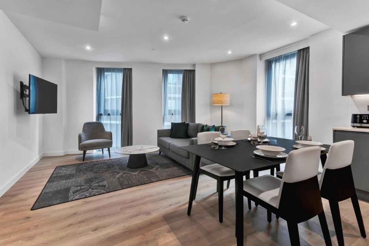 Citysuites 2 Aparthotel Manchester Exterior foto The photo shows a modern living space that includes a living area and dining area. 

- **Living Area**: There's a gray sofa with a coffee table in front of it, along with a single armchair. A large flat-screen TV is mounted on the wall. The space is 