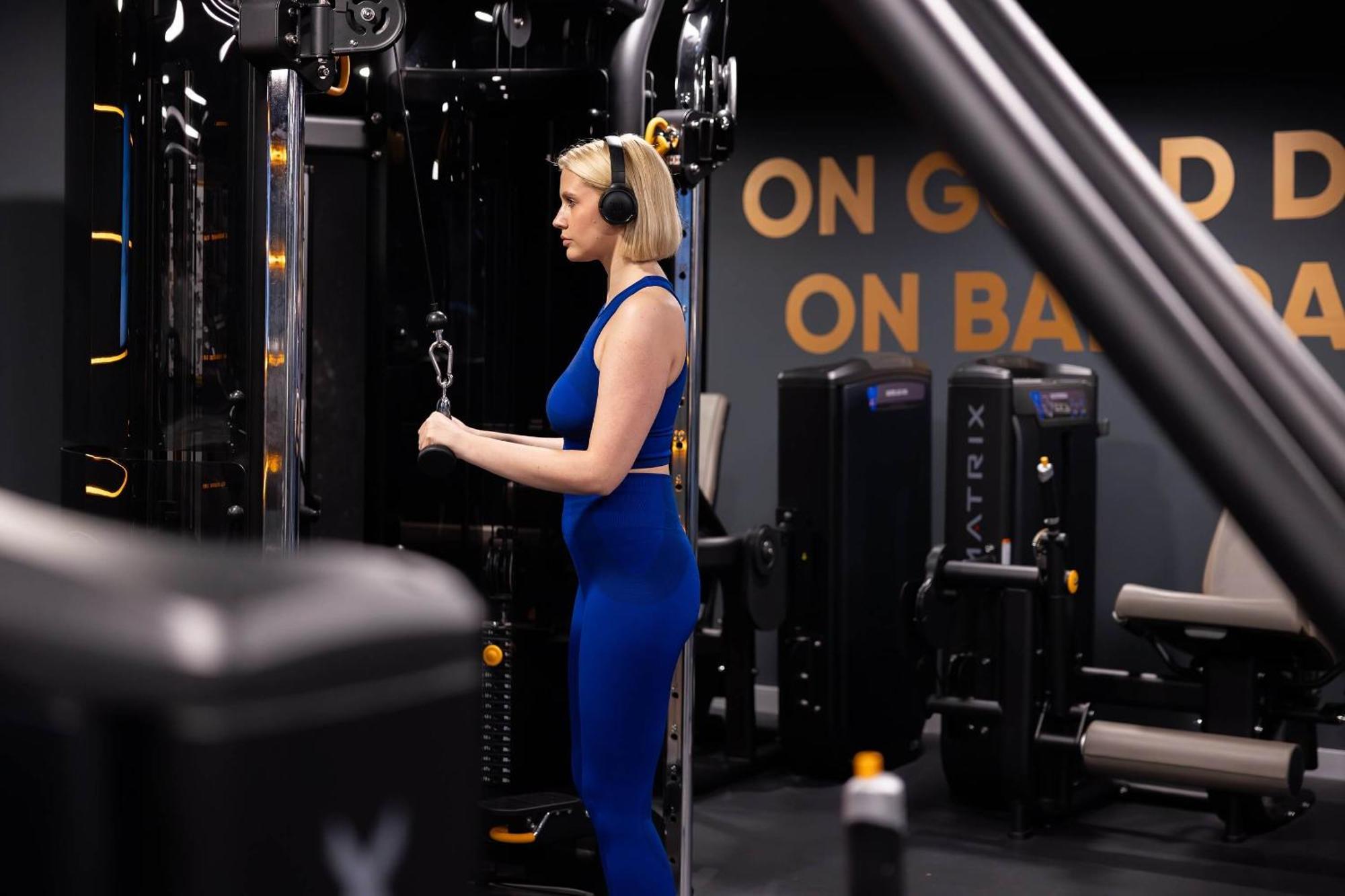 Citysuites 2 Aparthotel Manchester Exterior foto The photo shows a woman working out in a gym. She is wearing a blue athletic outfit and headphones while using a gym machine. The background features various other gym equipment and a wall with the words "ON GOOD ON BAD" displayed prominently. The se