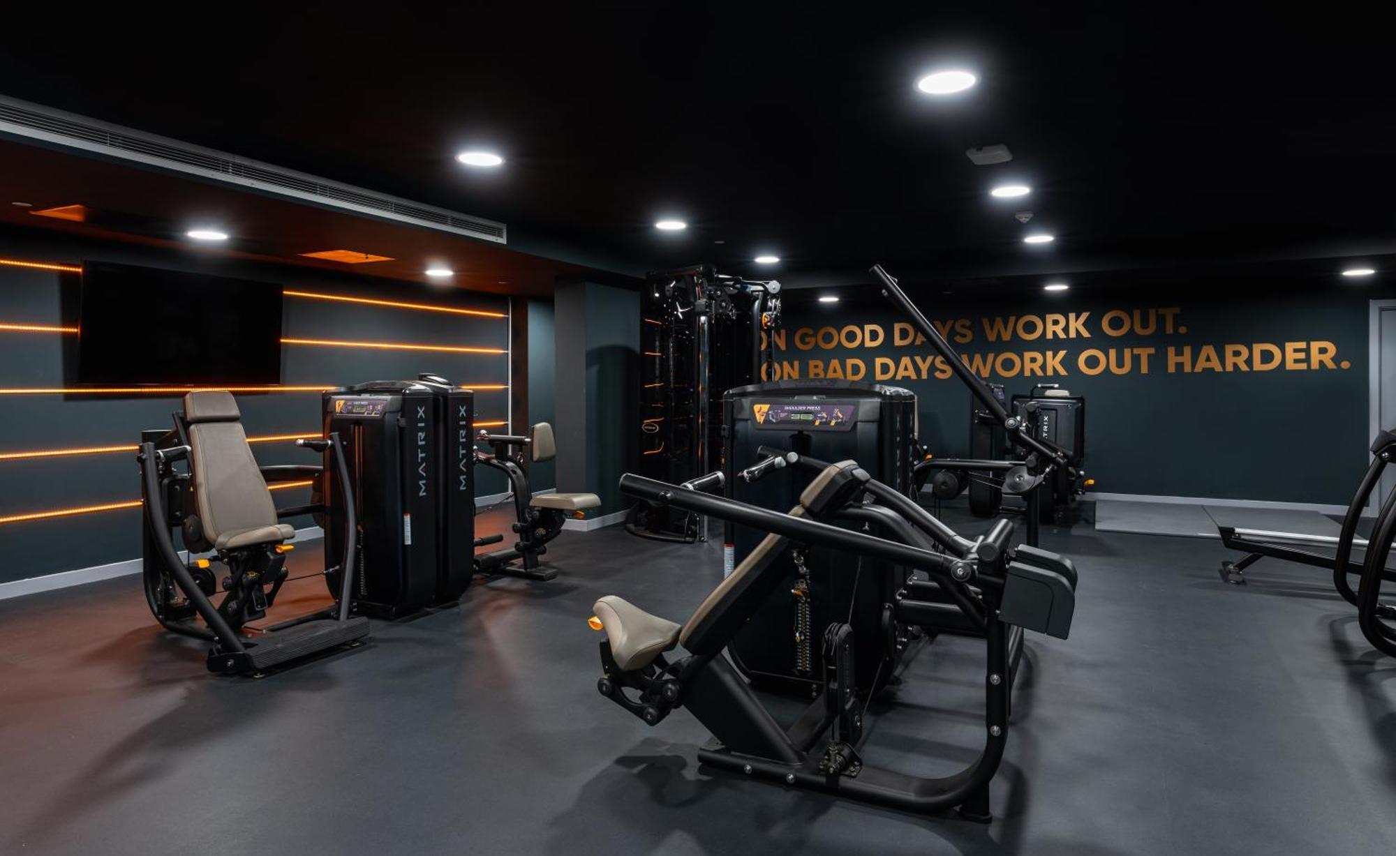 Citysuites 2 Aparthotel Manchester Exterior foto The photo shows a modern gym interior. The gym features various exercise machines, including weight training equipment. The flooring is dark, and the walls are adorned with motivational text that reads, "ON GOOD DAYS WORK OUT. ON BAD DAYS WORK OUT HA